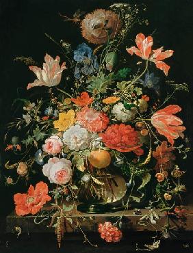Een glas met bloemen en een sinaasappeltak